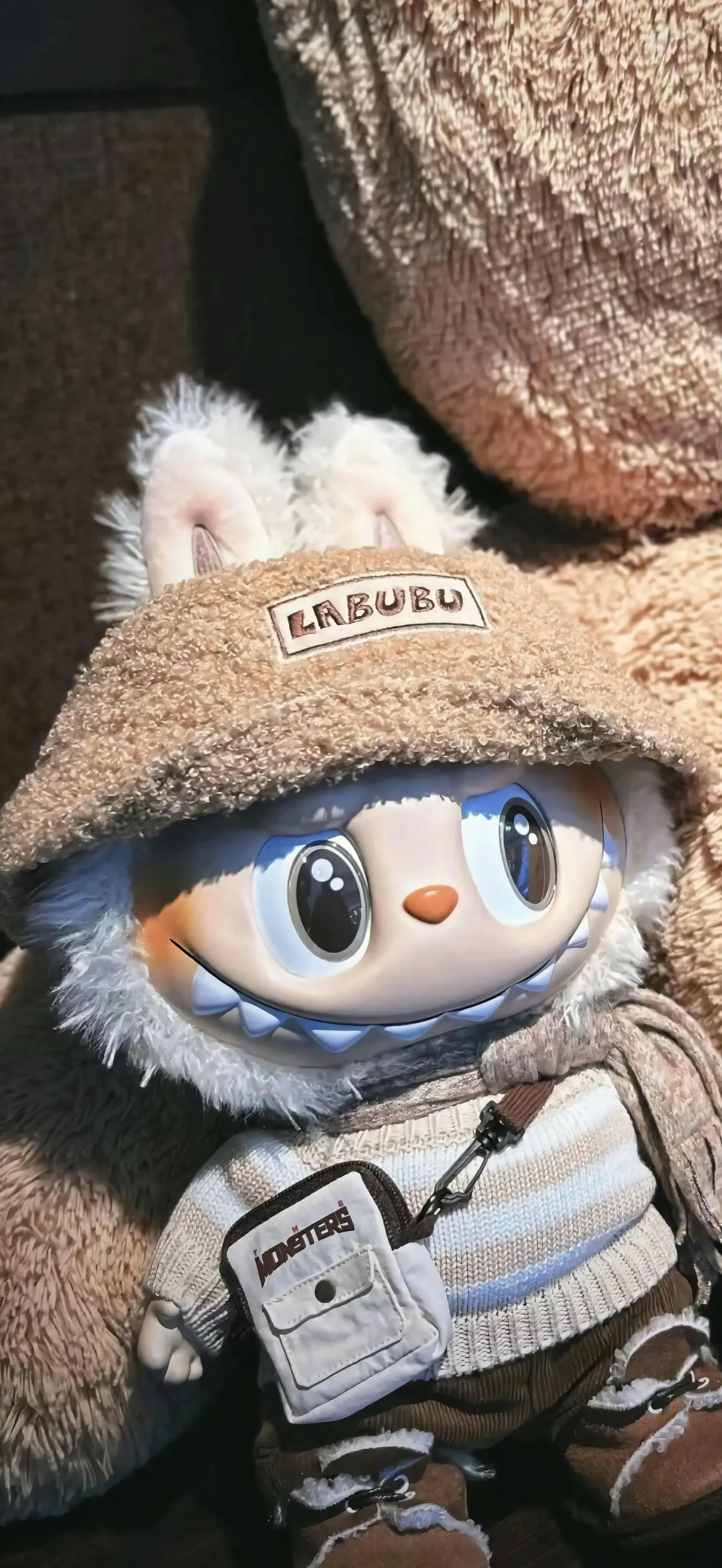 Cream white Labubu with bucket hat and sweater in a plush, cozy indoor scene
