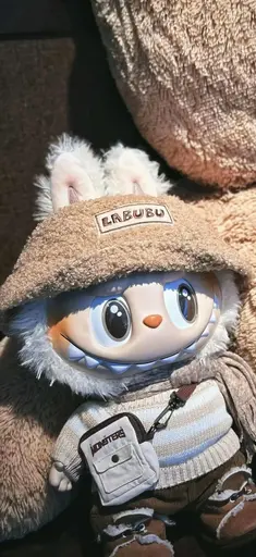 Cream white Labubu with bucket hat and sweater in a plush, cozy indoor scene